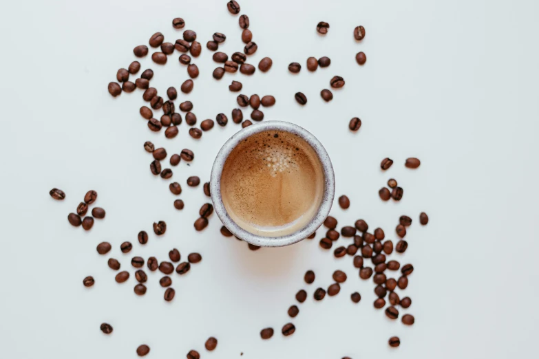 a cup of coffee surrounded by coffee beans, by Emma Andijewska, trending on unsplash, on white, background image, minimalist photo