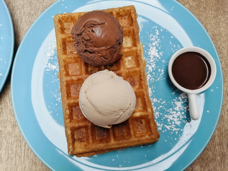 a waffle sitting on top of a blue plate next to a cup of coffee, ice cream on the side, 3 heads, chocolate, ice cream