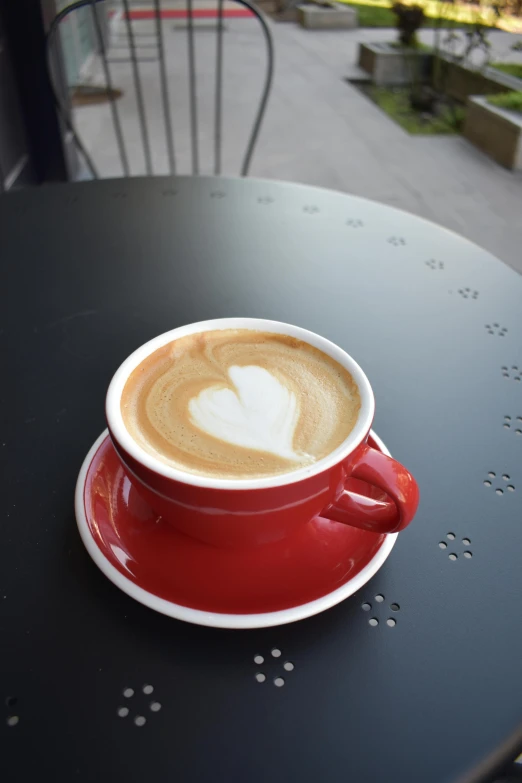 a cup of coffee sitting on top of a table, red and white, upon a peak in darien, exterior shot, various colors