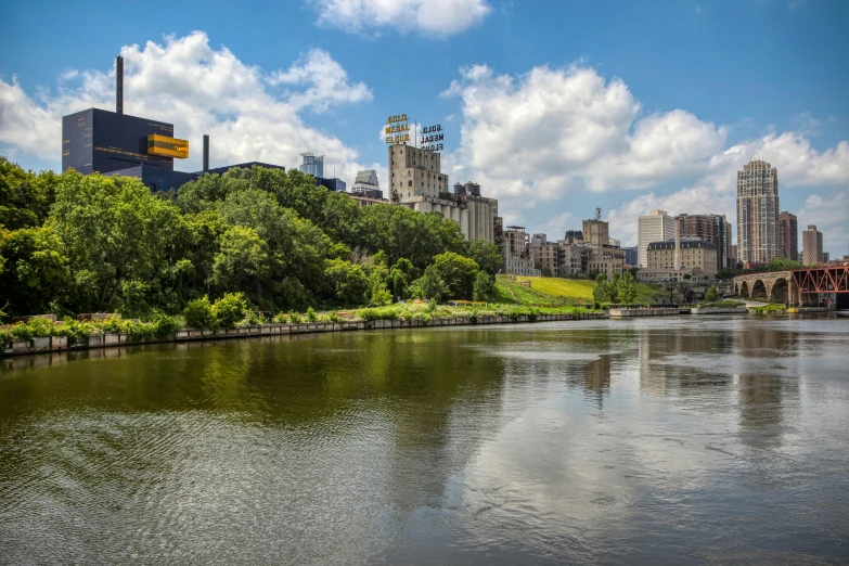 a body of water with buildings in the background, a photo, minneapolis, on a riverbank, 2022 photograph, scenery