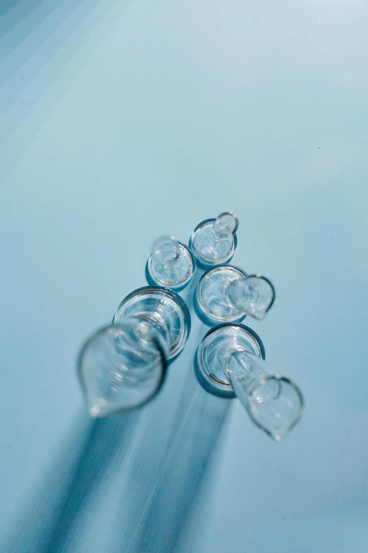 a bunch of glasses sitting on top of a table, syringe, detailed product image, clear blue water, detail shot