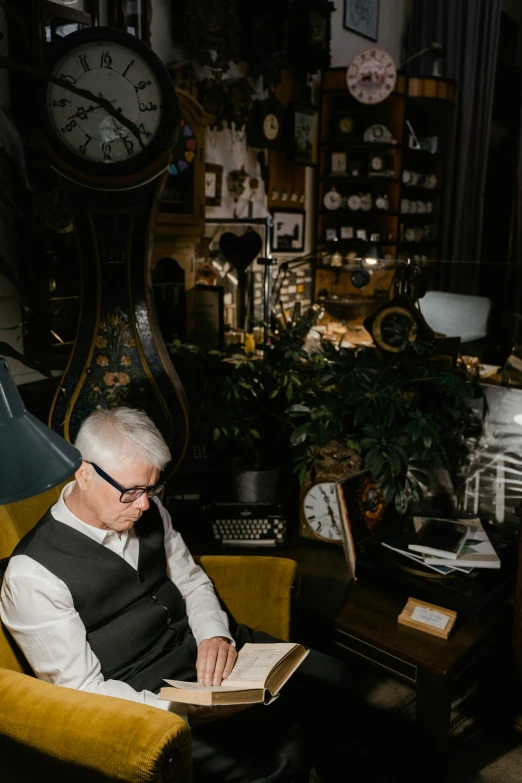 a man sitting in a chair reading a book, by Matt Cavotta, vanitas, a steampunk store, family photo, indoor setting, dark grey haired man