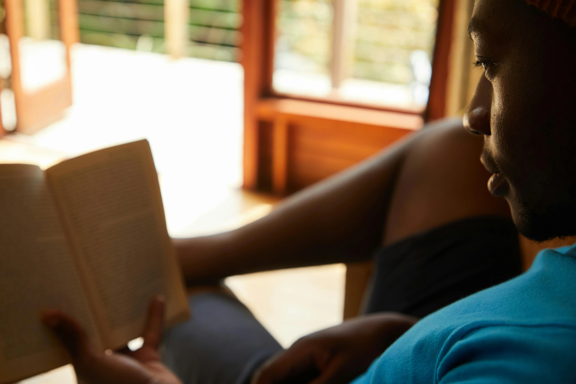 a person sitting in a chair reading a book, african woman, slightly out of focus, 30 year old man, engaging