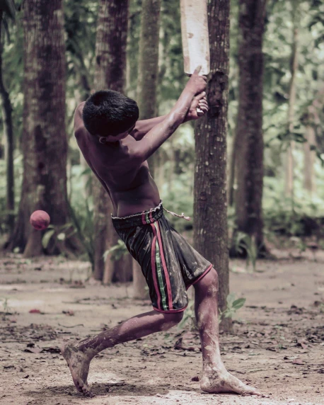 a man swinging a baseball bat at a ball, inspired by Steve McCurry, pexels contest winner, sumatraism, wearing loincloth, indian forest, childhood memory, lgbtq