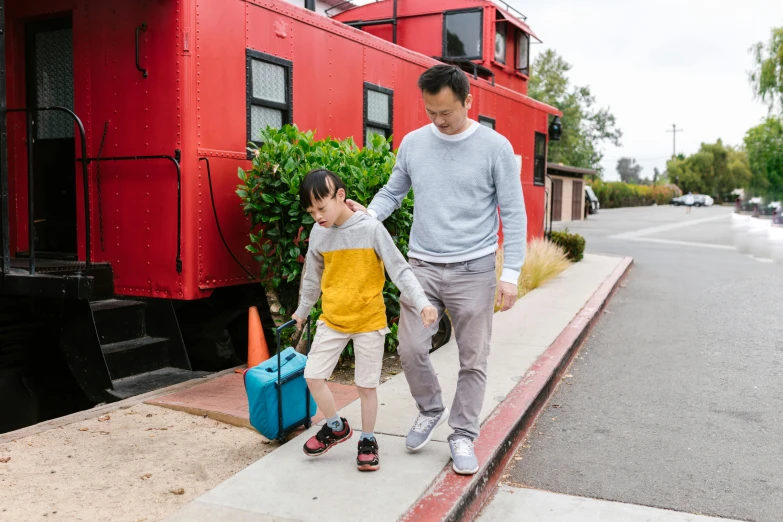 a man and a child walking next to a train, pexels contest winner, red sweater and gray pants, avatar image, luggage, full body photograph