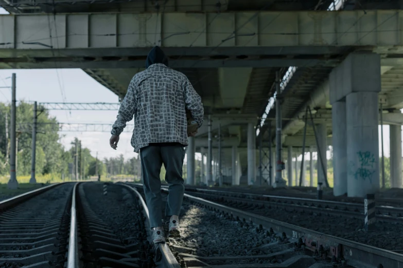 a man is walking down the train tracks, inspired by maxim verehin, unsplash, graffiti, still from the film, wearing dirty travelling clothes, worksafe. cinematic, azamat khairov
