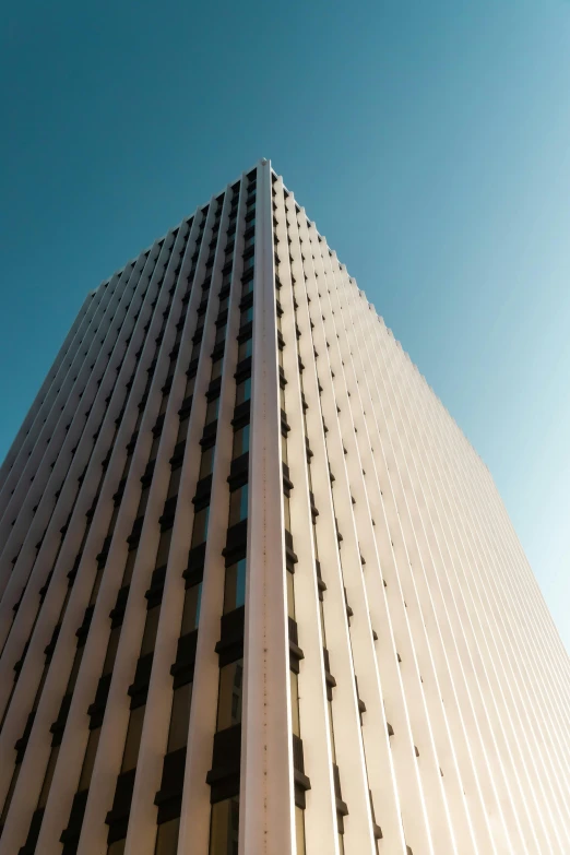 a tall building with a blue sky in the background, an album cover, unsplash, brutalism, brown, minn, high-angle, front lit