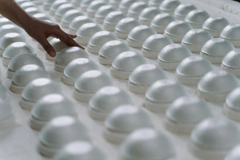a person touching the top of a tray of eggs, inspired by Vanessa Beecroft, trending on unsplash, process art, white foam, domes, factories, in a row