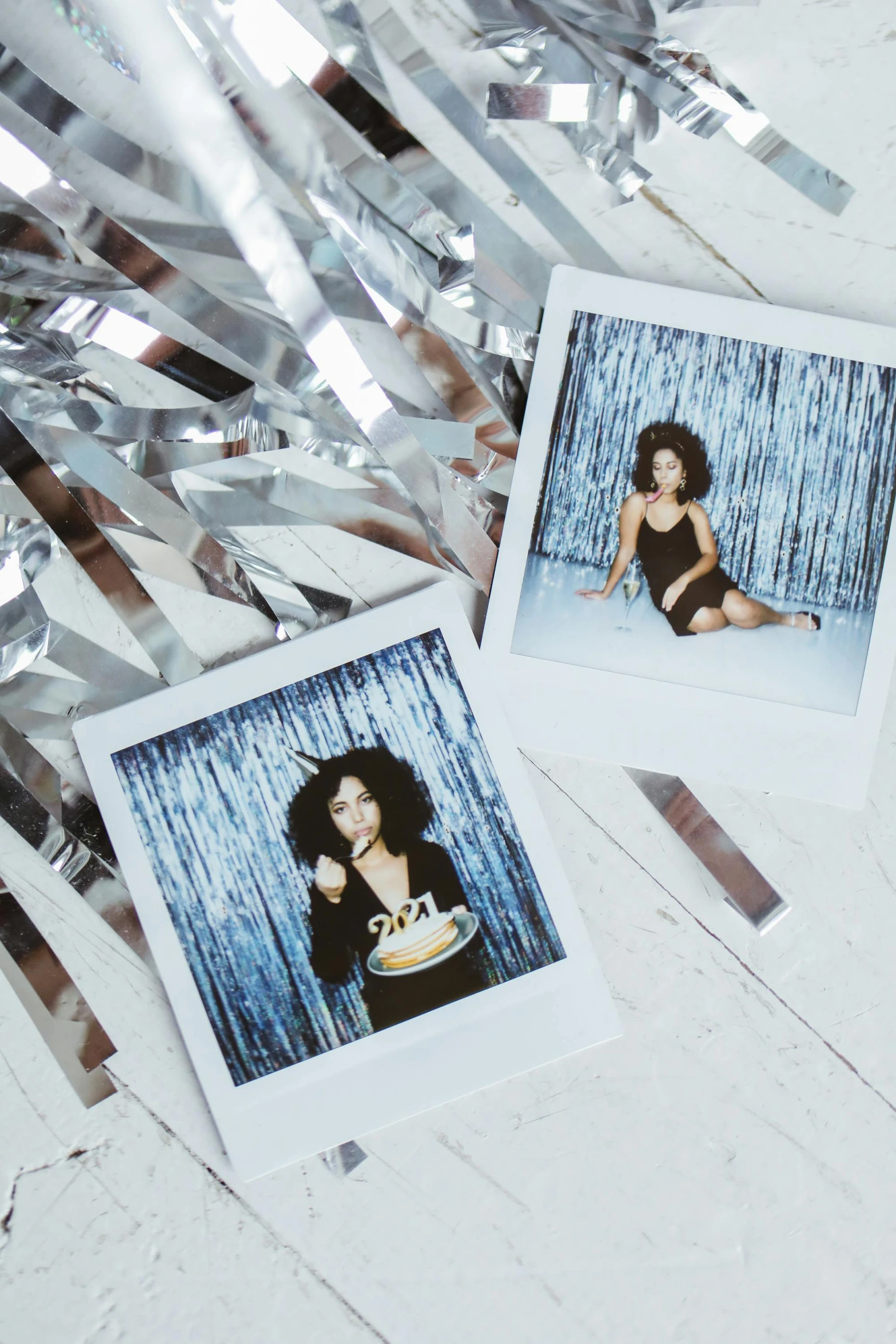 a couple of polaroids sitting on top of a table, a polaroid photo, inspired by Daphne Allen, glittering silver ornaments, nathalie emmanuel, disco party, ice cold blue theme