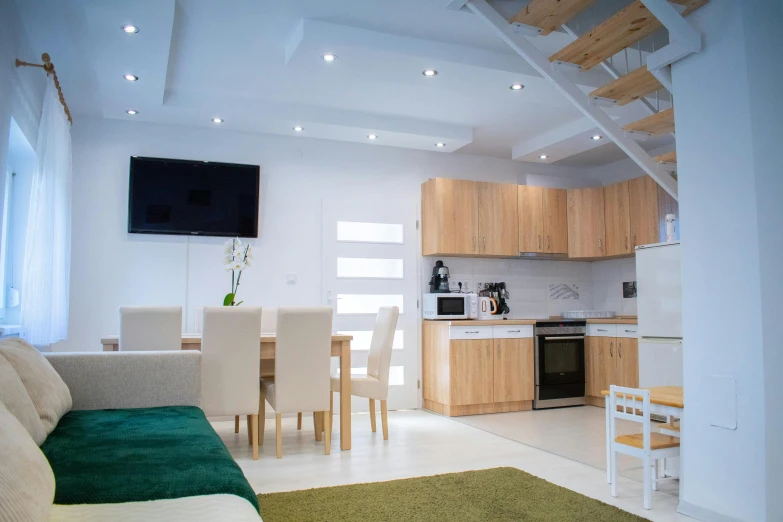 a living room filled with furniture and a flat screen tv, by Adam Marczyński, pexels contest winner, light and space, stairs to an upper floor, kitchenette and conferenceroom, clean 4 k, soft green natural light