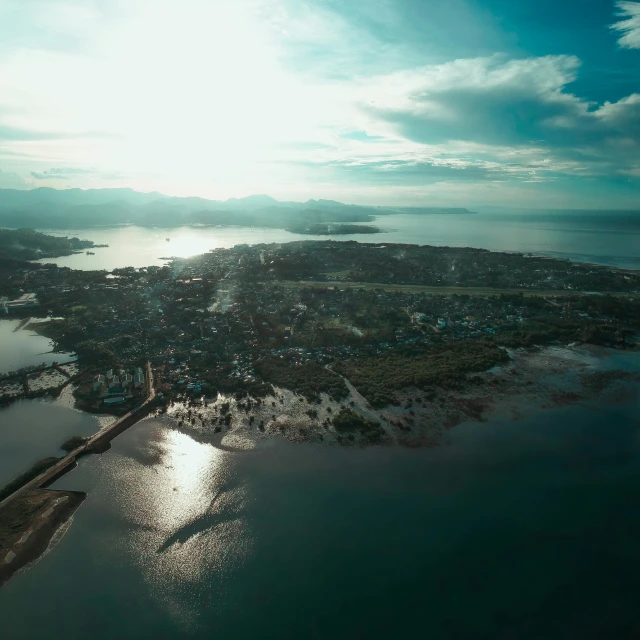 an aerial view of a large body of water, by Jakob Gauermann, pexels contest winner, hurufiyya, manila, small town surrounding, with the sun shining on it, coast as the background