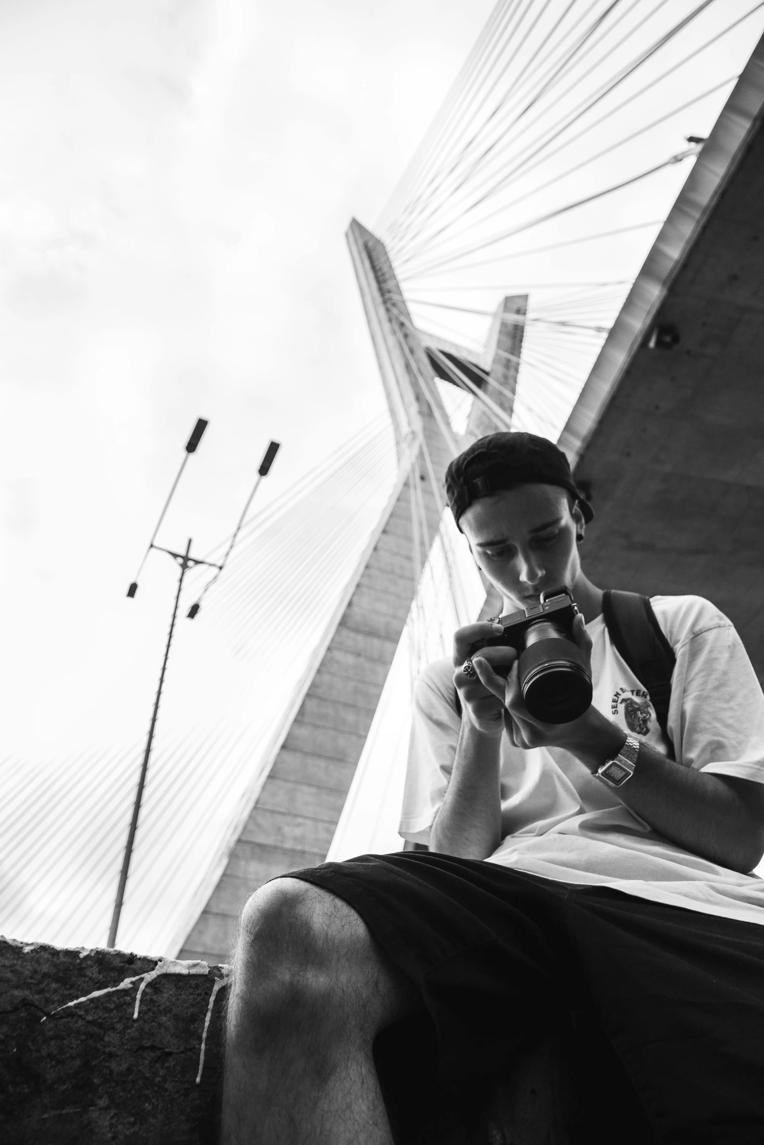 a black and white photo of a man holding a camera, a black and white photo, by Nadir Afonso, on a birdge, having a snack, rapping, mateus 9 5