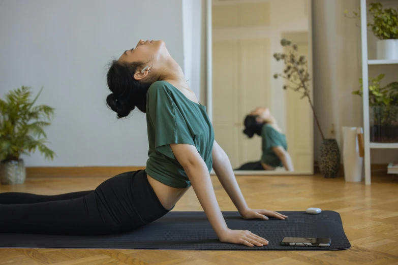 a woman doing a yoga pose in front of a mirror, a picture, unsplash, figuration libre, she is laying on her back, an asian woman, sideview, low quality photo