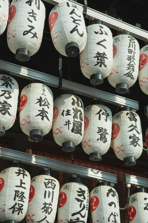 a wall filled with lots of white and red paper lanterns, a picture, inspired by Sesshū Tōyō, sōsaku hanga, with white kanji insignias, evening sunlight, teaser, stacks