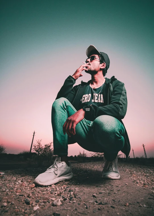 a man sitting on the ground smoking a cigarette, trending on pexels, realism, wearing sunglasses and a cap, green smoggy sky, profile picture, riyahd cassiem