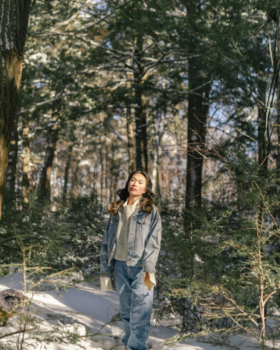 a woman walking through a snow covered forest, an album cover, inspired by Ma Yuanyu, trending on unsplash, wearing blue jean overalls, portrait mode photo, ✨🕌🌙, joy ang