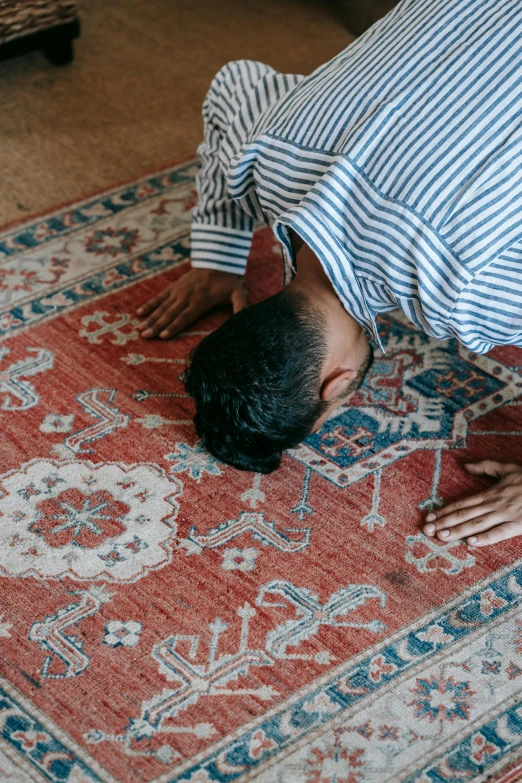 a man laying on top of a rug on the floor, hurufiyya, doing a prayer, head down, red carpeted floor, headspace