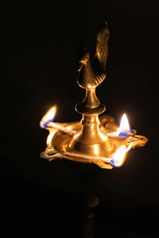 a candle that is lit in the dark, hindu art, emerging from a lamp, gold and black metal, nadir lighting