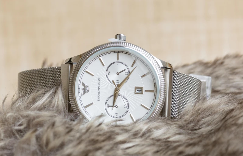 a close up of a watch on a furry surface, a portrait, inspired by Eugène Brands, trending on pexels, armani, white and silver, grain”