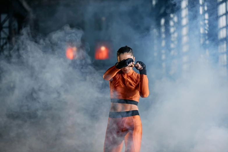 a woman in an orange outfit holding a camera, by Julia Pishtar, pexels contest winner, wrestlers wearing vr headsets, smoke and atmosphere, ninja warrior, unreal engine : : rave makeup