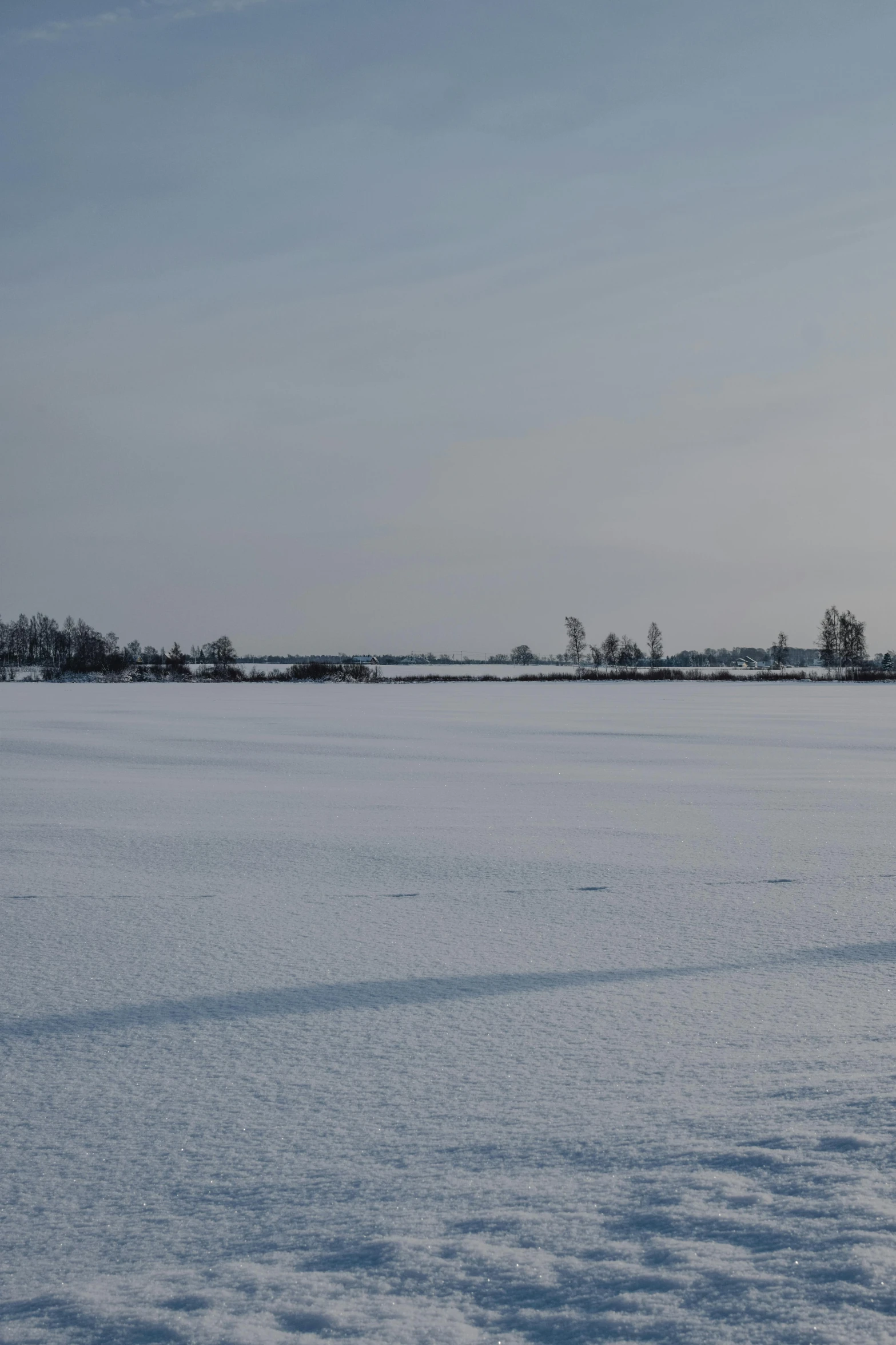 a man riding a snowboard across a snow covered field, by Daarken, land art, viewed from afar, helmond, farm land, grey