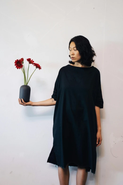 a woman holding a vase with a flower in it, an album cover, inspired by Kim Tschang Yeul, unsplash, casual black clothing, organic dress, kasumi arimura style 3/4, nishihara isao