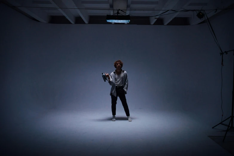 a woman standing in a dimly lit room, inspired by Russell Dongjun Lu, unsplash, video art, battle pose, trippie redd, performing a music video, in a white room