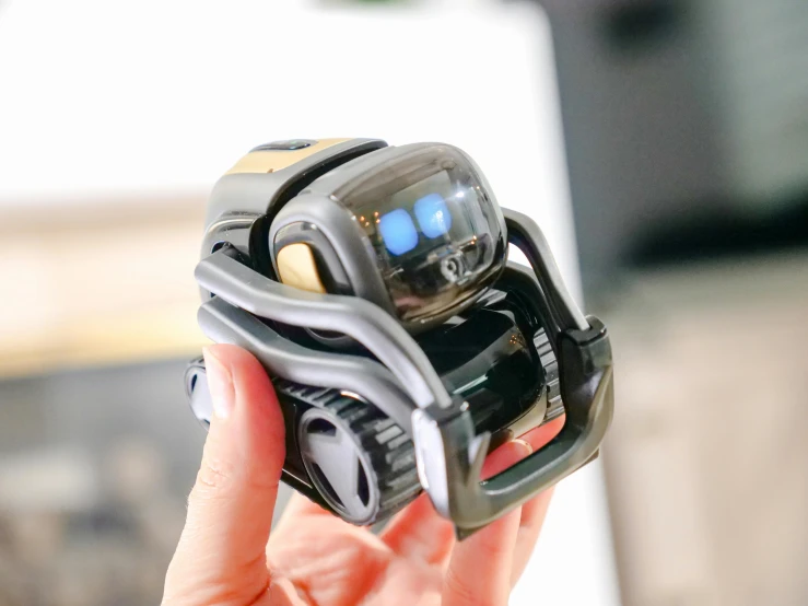 a person holding a camera in their hand, a hologram, by Julia Pishtar, unsplash, cute robot wooden, glados, made of smooth black goo, robot dog