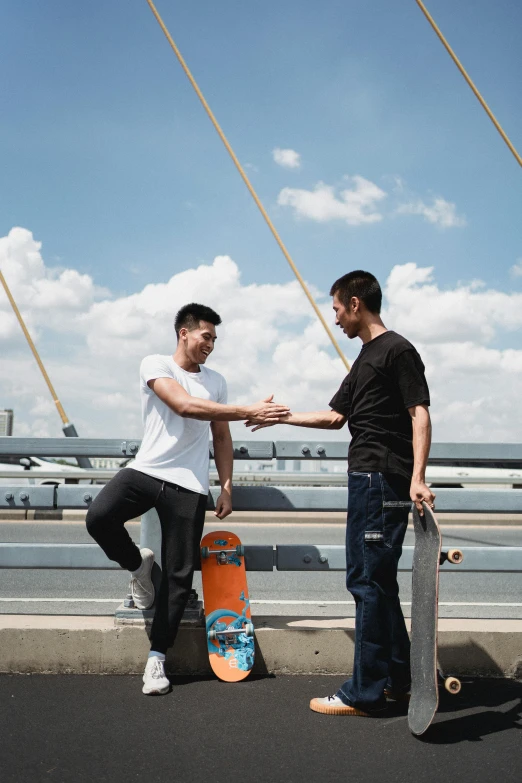 a couple of men standing next to each other on a bridge, standing on a skateboard, qi sheng luo, reaching out to each other, asher duran