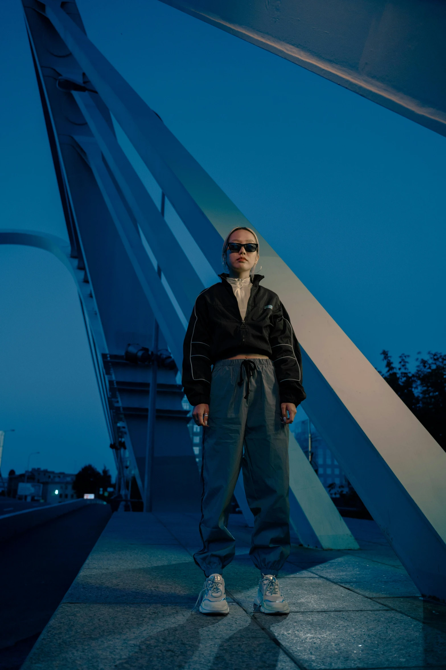 a man standing in front of a bridge at night, an album cover, neo-dada, bad bunny, high quality photo, a portrait of issey miyake, blue sky