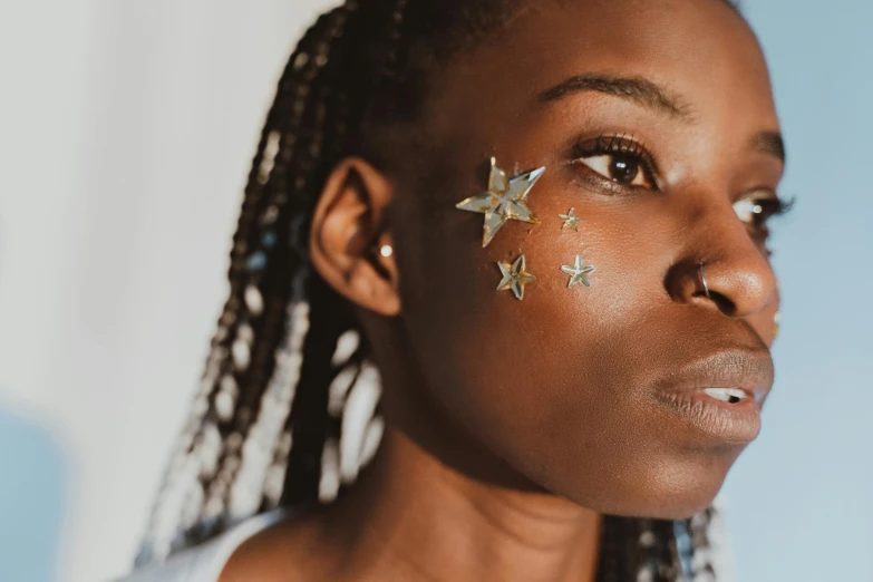 a woman with gold stars on her face, by Julia Pishtar, trending on pexels, afrofuturism, clean face and body skin, black teenage girl, iridescent skin, skincare