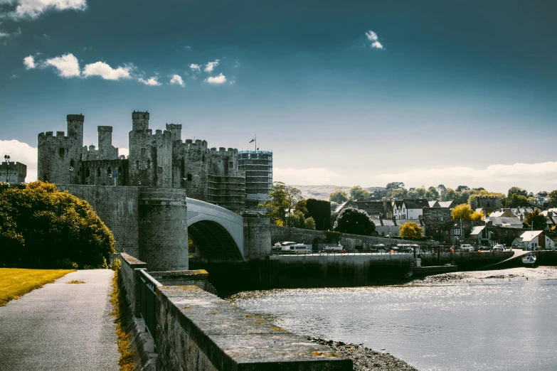 a bridge over a river with a castle in the background, by Ben Thompson, pexels contest winner, caernarfon castle, thumbnail, wide high angle view, high - contrast