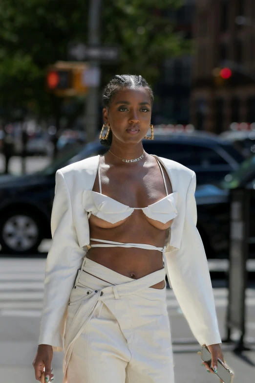 a woman in a white suit is walking down the street, an album cover, trending on unsplash, renaissance, bare midriff, willow smith young, covered breasts, at new york fashion week