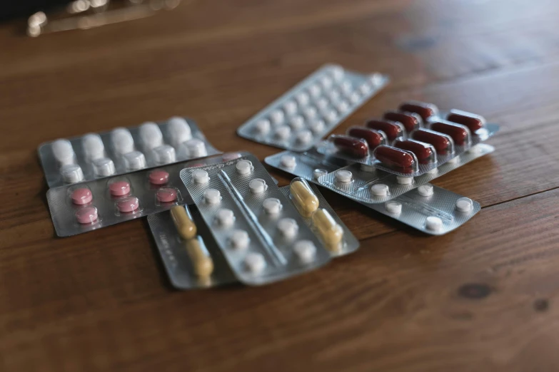 a bunch of pills sitting on top of a wooden table, by Adam Marczyński, antipodeans, realistic materials, really realistic, medical equipment, varying thickness