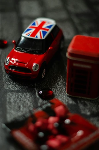 a red toy car sitting on top of a table, by David Donaldson, unsplash, union jack, squashed berries, r / paintedminis, detail on scene