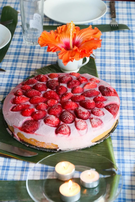 a table topped with a cake covered in strawberries, kauai, flower power, medium close up, ready to eat