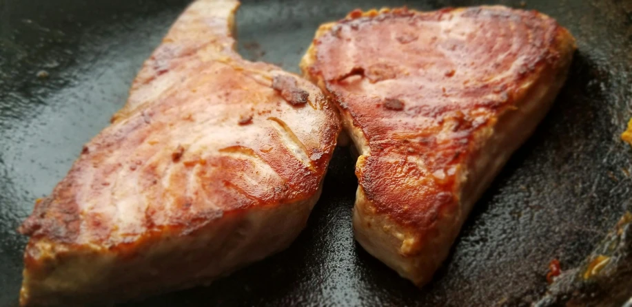 two pieces of meat cooking in a frying pan, a picture, by Tom Wänerstrand, unsplash, sōsaku hanga, chiseled jaw, gray mottled skin, けもの, made of glazed