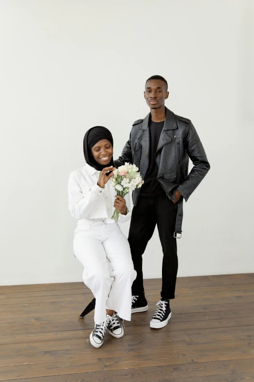 a man and a woman standing next to each other, hurufiyya, wearing a hoodie and flowers, white and black color palette, holding flowers, wearing human air force jumpsuit