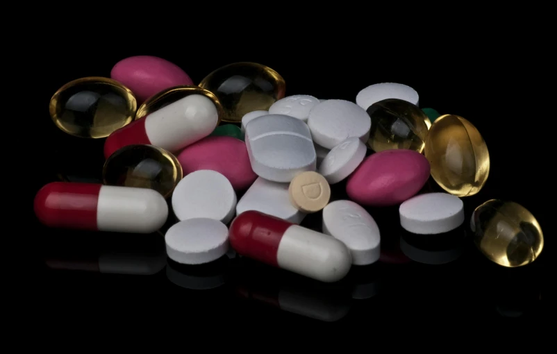 a pile of pills and capsules on a black surface, by Elizabeth Durack, pexels, photorealism, multi colour, white, vessels, black