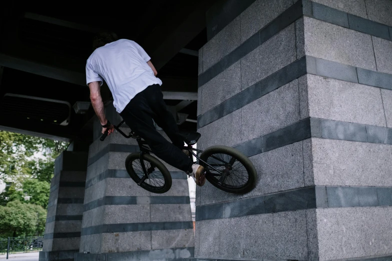 a man flying through the air while riding a bike, unsplash, realism, on a large marble wall, brown, blunt, casey cooke