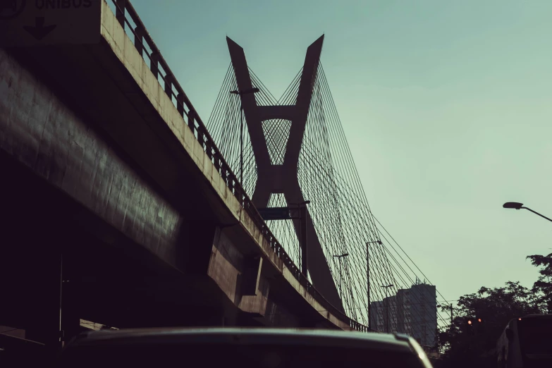 a car driving down a street next to a bridge, an album cover, by Jacob Toorenvliet, pexels contest winner, streets of calcutta, brutal archi, connecting lines, fine delicate structure