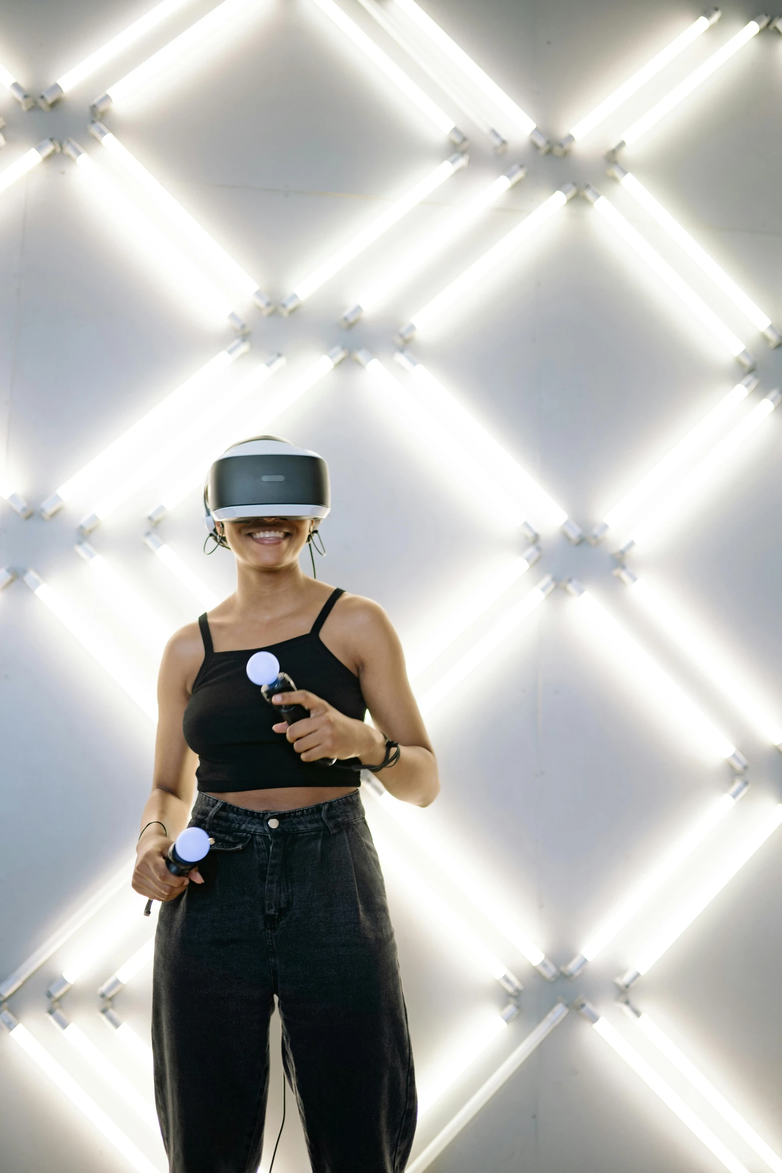 a woman standing in front of a wall with lights, a hologram, unsplash, interactive art, vr helmet on man, rapping on stage at festival, brilliant daylight vr os ux, “zendaya