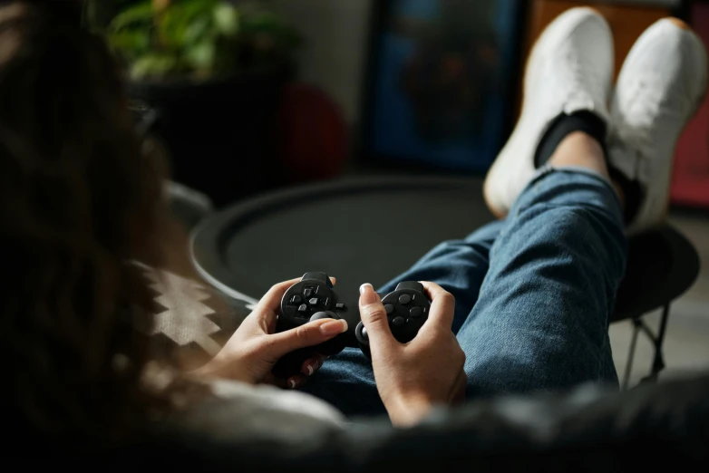 a woman sitting in a chair holding a video game controller, trending on pexels, laying down with wrists together, instagram photo, cinematic still, casual game