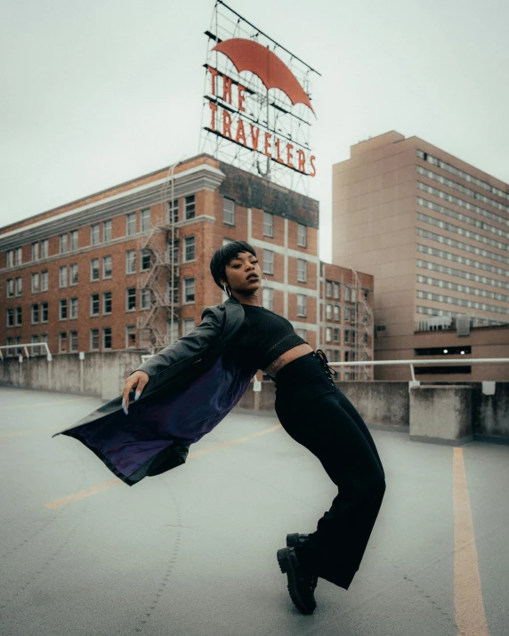 a man standing on top of a roof next to a tall building, an album cover, unsplash, an epic non - binary model, wearing black and purple robes, classic dancer striking a pose, he is wearing a trenchcoat