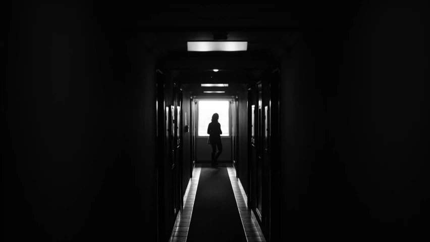 a black and white photo of a person in a hallway, by Matthias Weischer, pexels contest winner, female cyborg black silhouette, capsule hotel, instagram picture, hotel room