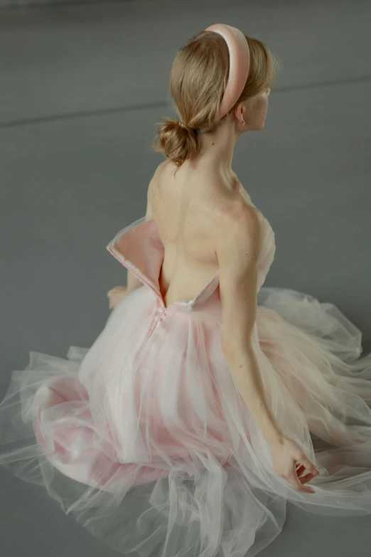 a woman in a pink dress sitting on the floor, by Elizabeth Polunin, showing her shoulder from back, tutu, detail shot, tn
