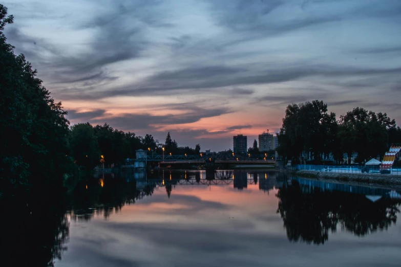 a large body of water surrounded by trees, by Antoni Brodowski, pexels contest winner, romanticism, city twilight landscape, high resolution photo, grey, multiple stories