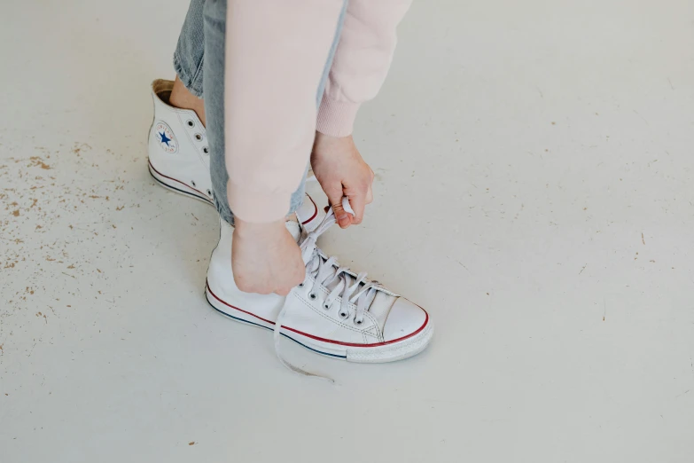 a close up of a person tying a shoe, trending on pexels, antipodeans, white and pink, girl standing, high resolution photo, converse