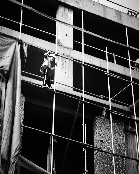 a black and white photo of a man on a scaffolding, unsplash, brutalism, tehran, puppet on a string, worksafe. instagram photo, instagram post