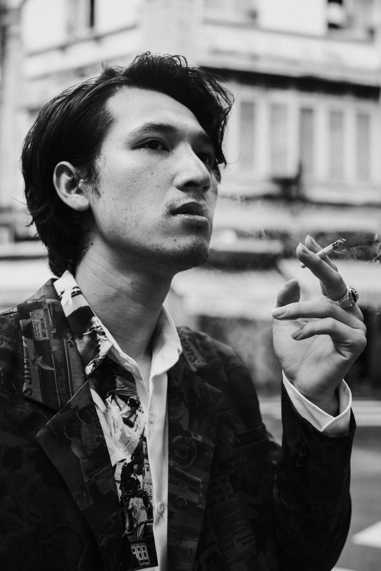 a black and white photo of a man smoking a cigarette, inspired by Reuben Tam, mark edward fischbach, wearing a fancy jacket, photograph taken in 2 0 2 0, asian male